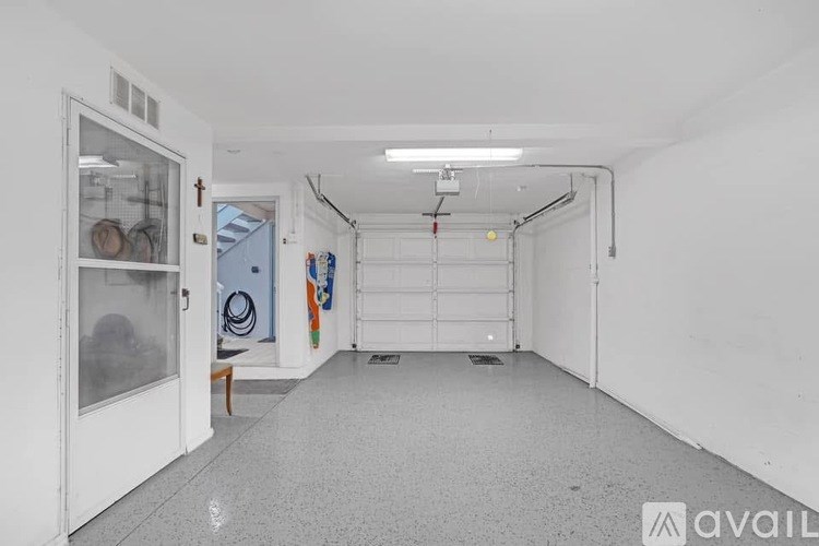 A long white hallway with a door on the left and a bench under a window.