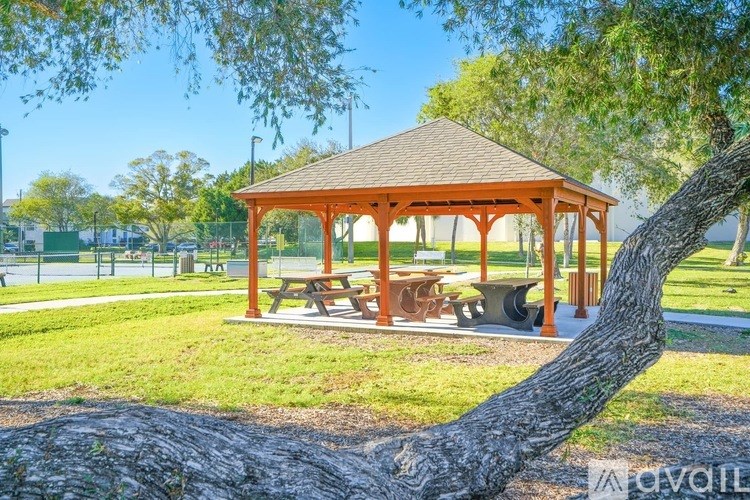 A wooden gazebo with a tree in front of it.