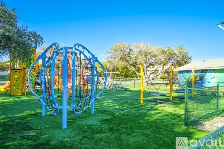 A playground with a blue and yellow climbing structure and a green lawn.