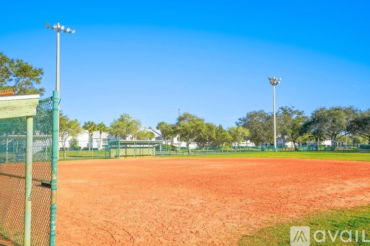 A tennis court with a green fence and two light poles.