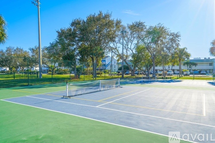 A tennis court surrounded by trees and a fence.