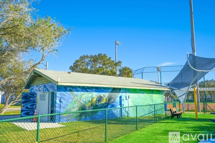 A baseball field with a green fence and a mural on the wall.