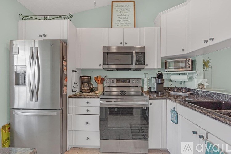 A kitchen with a refrigerator, oven, and microwave.