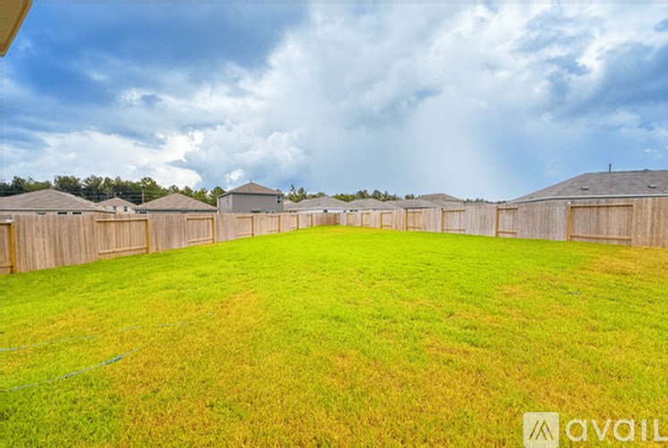 A backyard with a fence and a grassy field.