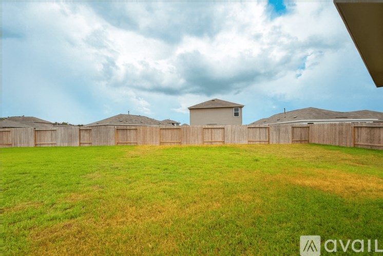 A backyard with a fence and a house in the background.
