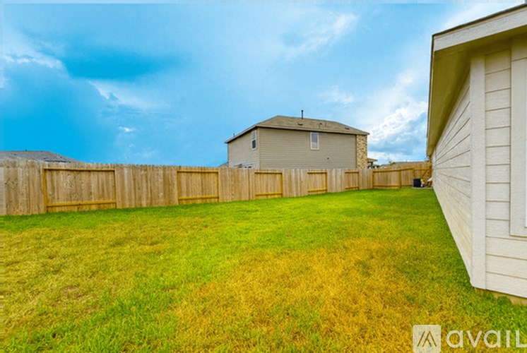 A backyard with a wooden fence and a house in the background.