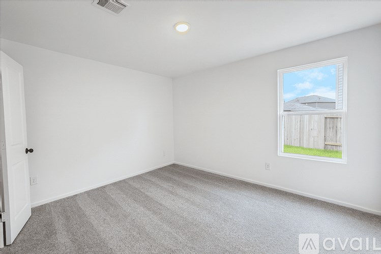 A room with a carpeted floor and a window showing a house.