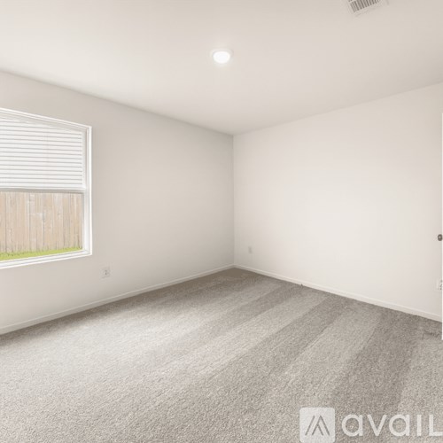 A room with a carpeted floor and a window with blinds.