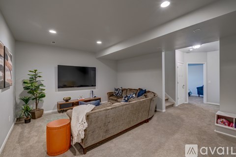 A living room with a couch, a television, and a potted plant.