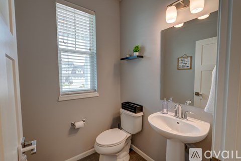A bathroom with a toilet, sink, and window.