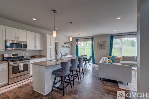 A kitchen with white cabinets and a large island with a bar stool.