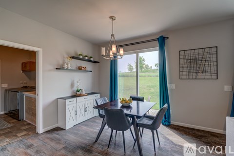 A dining area with a table set for two and a view of the backyard.