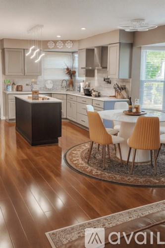 A kitchen with a black island and wooden floors.