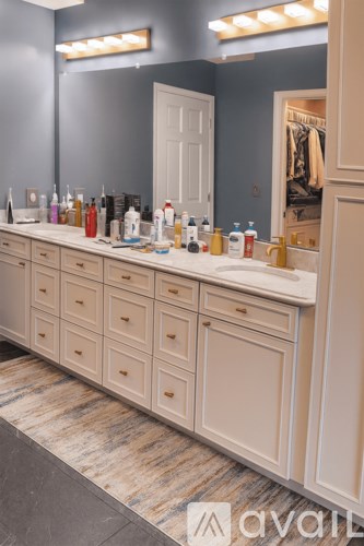 A bathroom vanity with a row of bottles on the counter.