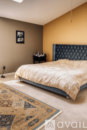 A bedroom with a bed, a rug, and a picture on the wall.
