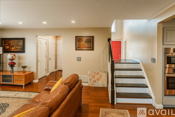 A house with a white exterior and a grey roof is surrounded by a fence and has a patio area with chairs and a table.