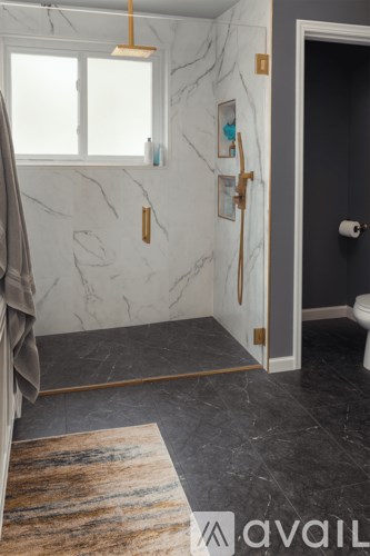 A bathroom with marble walls and a rug on the floor.
