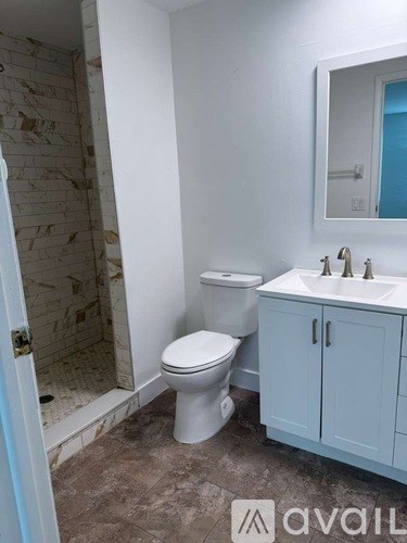 A bathroom with a toilet, sink, and a mirror.