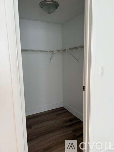 A small, empty room with a wooden floor and white walls.