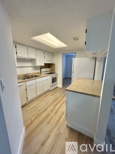 A kitchen with white cabinets and a wooden floor.