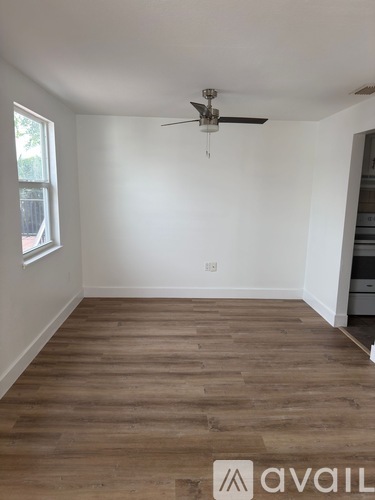 A room with a ceiling fan and wooden flooring.