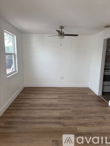 A room with a ceiling fan and wooden flooring.