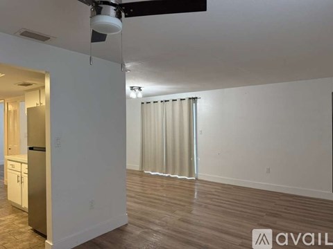 A room with a wooden floor and a white wall with a door on the left side.