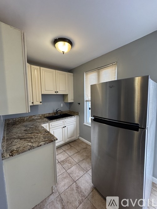 A kitchen with a granite counter top and a stainless steel refrigerator.