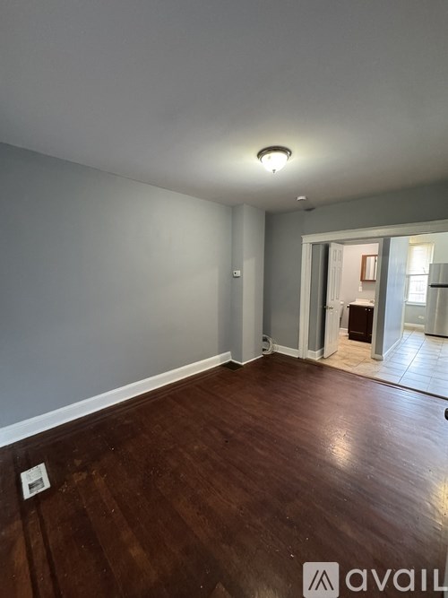 A room with wooden flooring and a white wall.