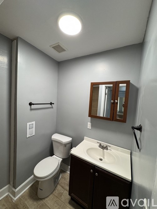 A bathroom with a toilet, sink, and mirror.