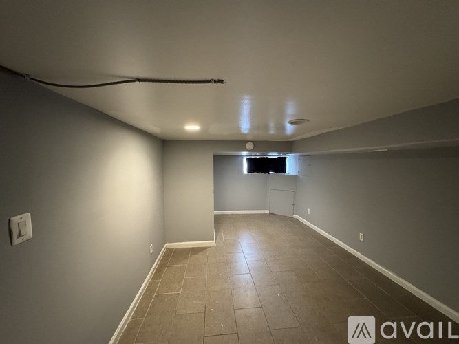 A spacious room with tiled flooring and a window in the distance.