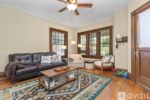 A living room with a black leather couch and a patterned rug.