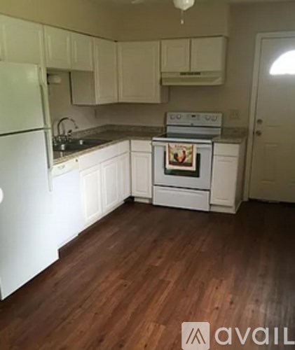 A kitchen with white appliances and wooden floors.
