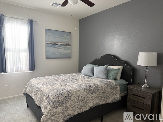 A bedroom with a bed, dresser, and a painting on the wall.