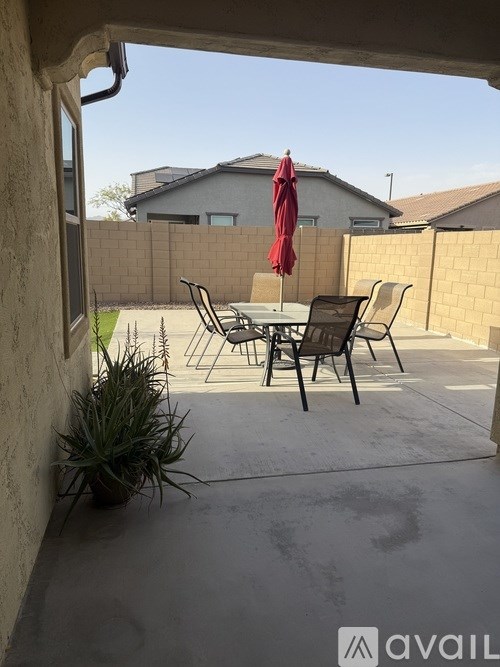 A patio with a table and chairs and a red umbrella.