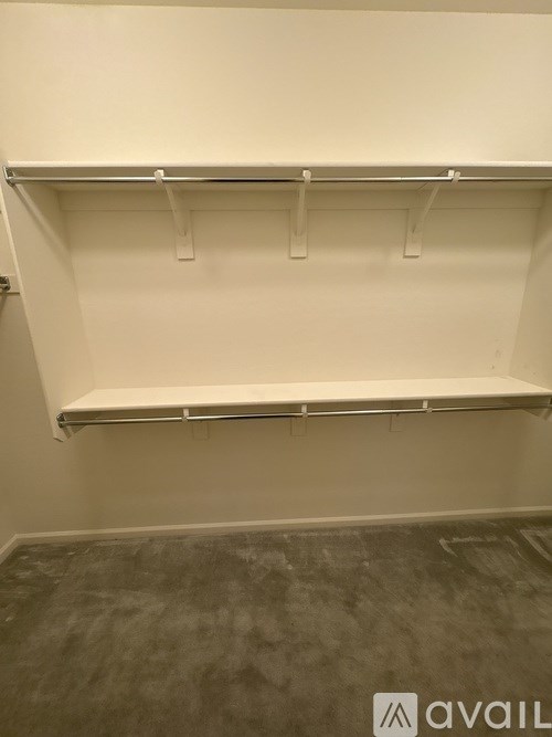 Empty white shelves in a room with grey carpet.