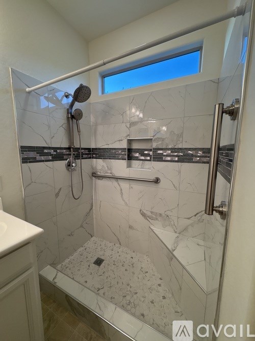 A bathroom with a marble shower and a window.