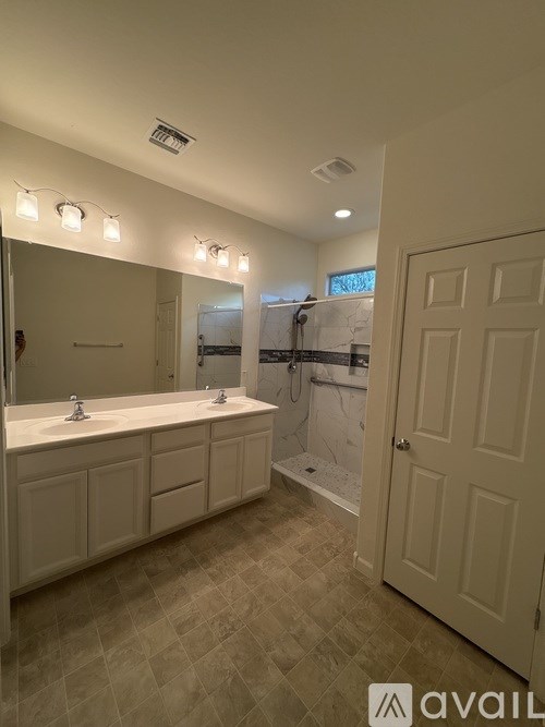 A bathroom with a large mirror and lights above it.