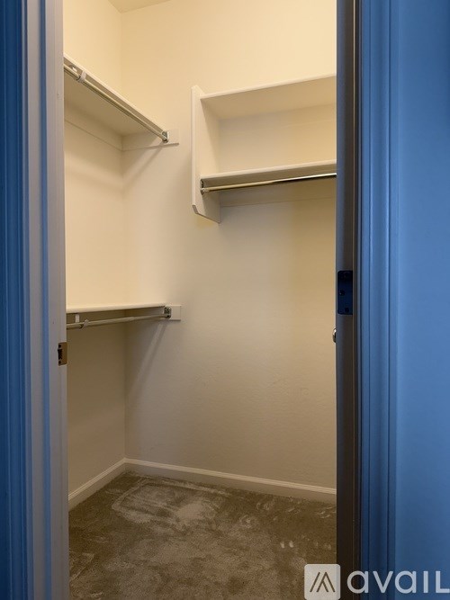 A small, empty room with a blue door and white walls.