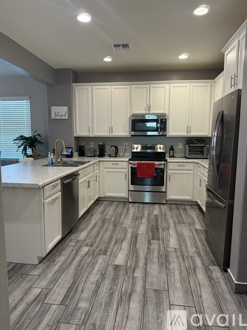 A modern kitchen with white cabinets and a grey floor.