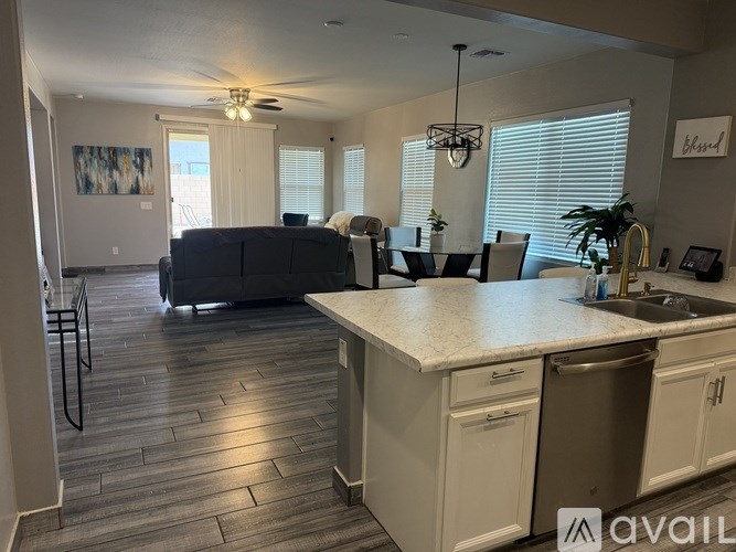 A kitchen with a white countertop and a grey couch.