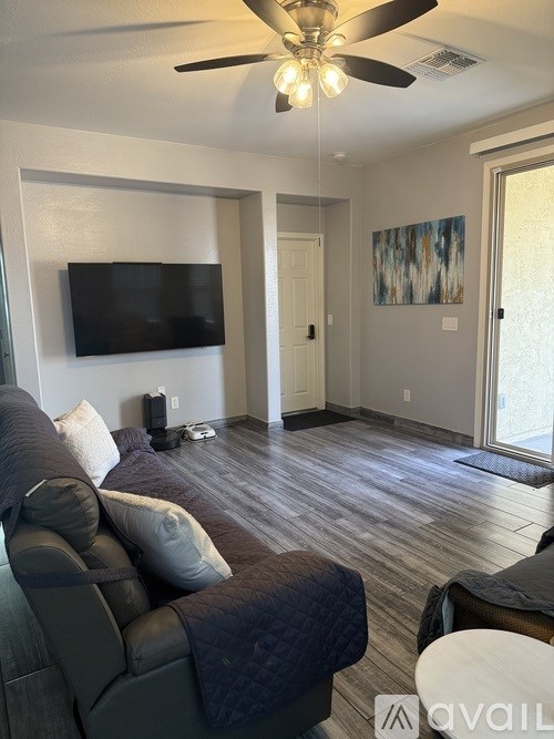 A living room with a grey couch and a flat screen TV mounted on the wall.