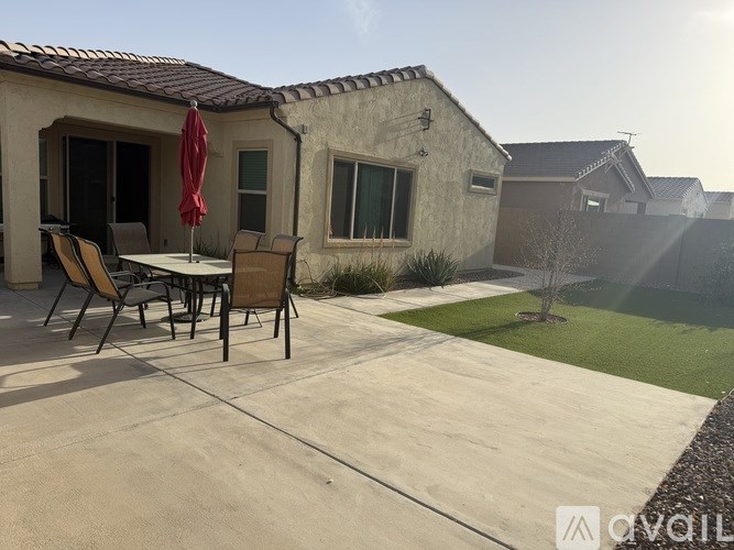 A patio with a table and chairs is in front of a house.