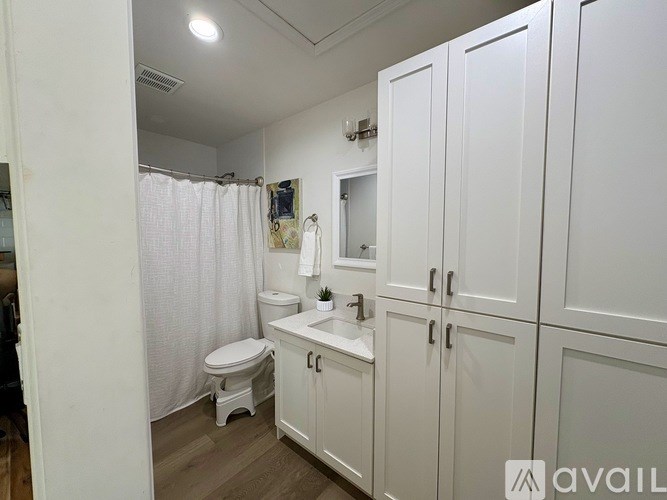 A white bathroom with a toilet, sink, and shower curtain.