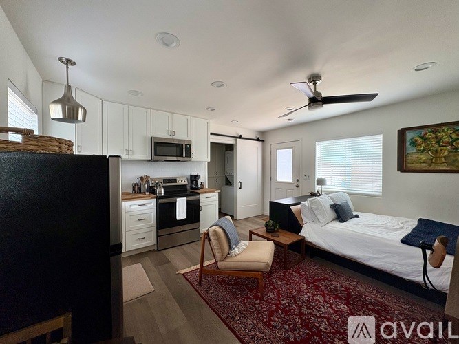 A bedroom with a bed, chair, and a ceiling fan.