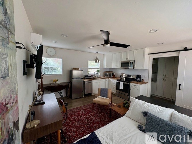 A bedroom with a bed, a desk, and a kitchen area.