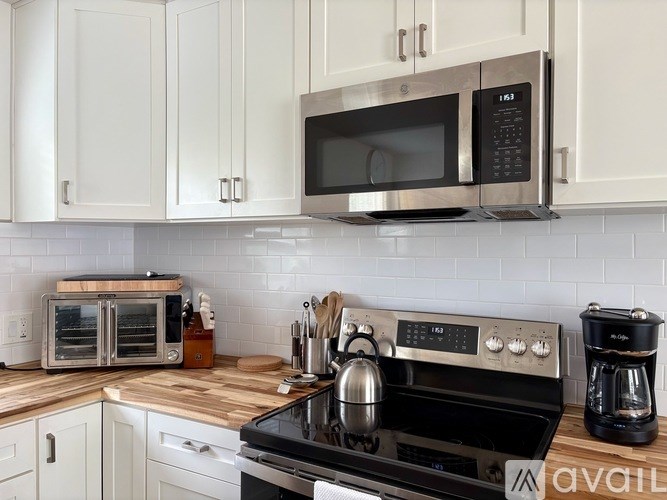 A kitchen with a black stove top oven, a black microwave, and white cabinets.