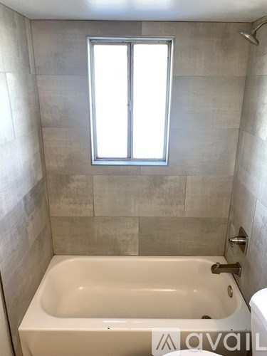 A bathroom with a tub, toilet and window.