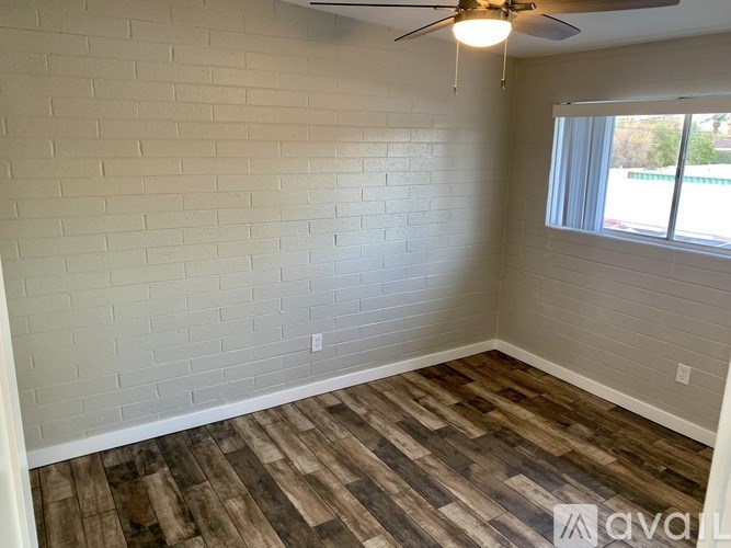 A room with a ceiling fan and wooden flooring.