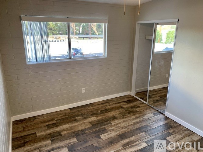 A room with a window and a wooden floor.